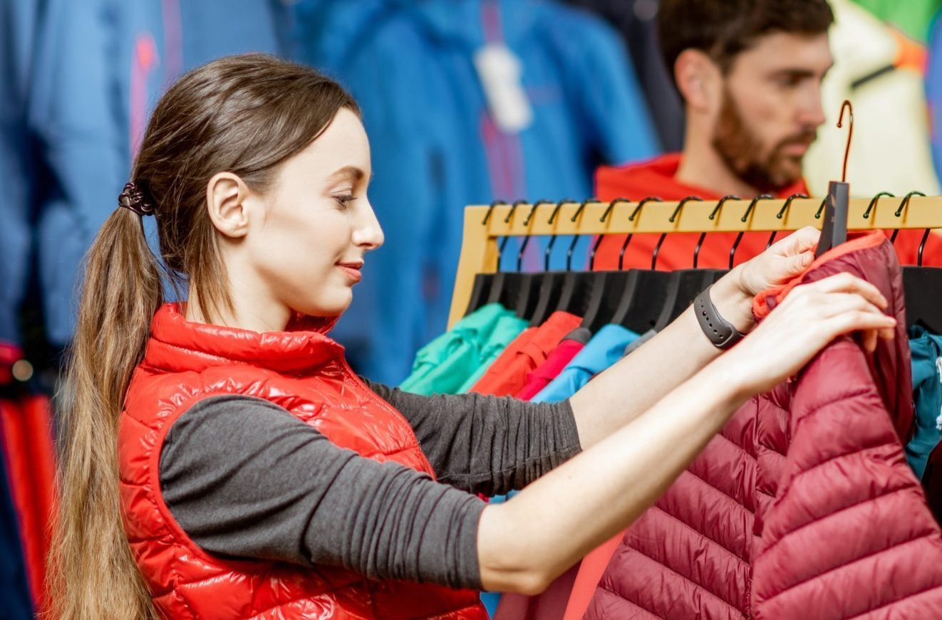 A woman shopping at Patagonia looking at a jacket with a designed hang tag.